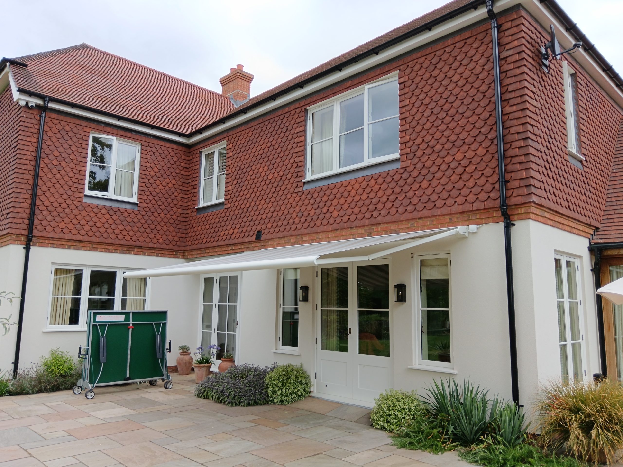 Slim white cassette awning retracted above the windows of a period London townhouse with black railings
