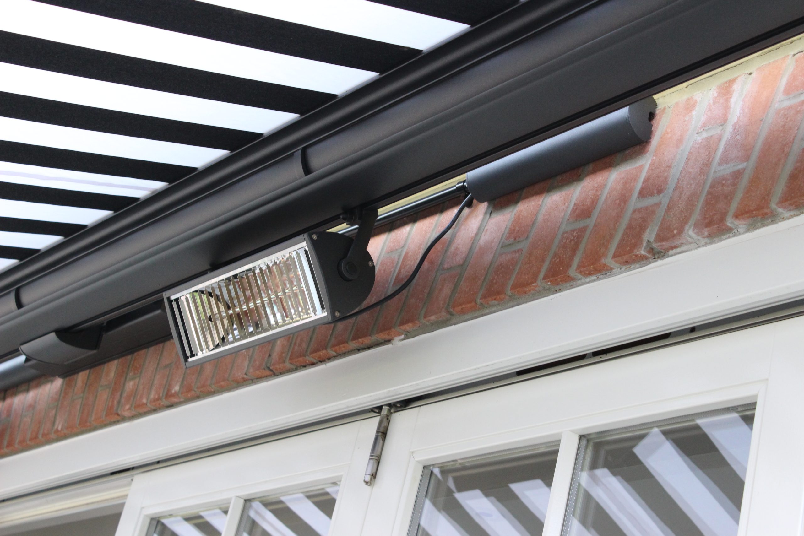 Awning with an infrared heater mounted under the front bar shading a garden dining table