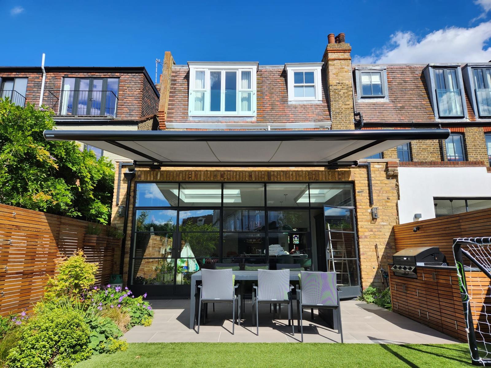 Cream striped retractable awning shading a white patio set outside bifold doors
