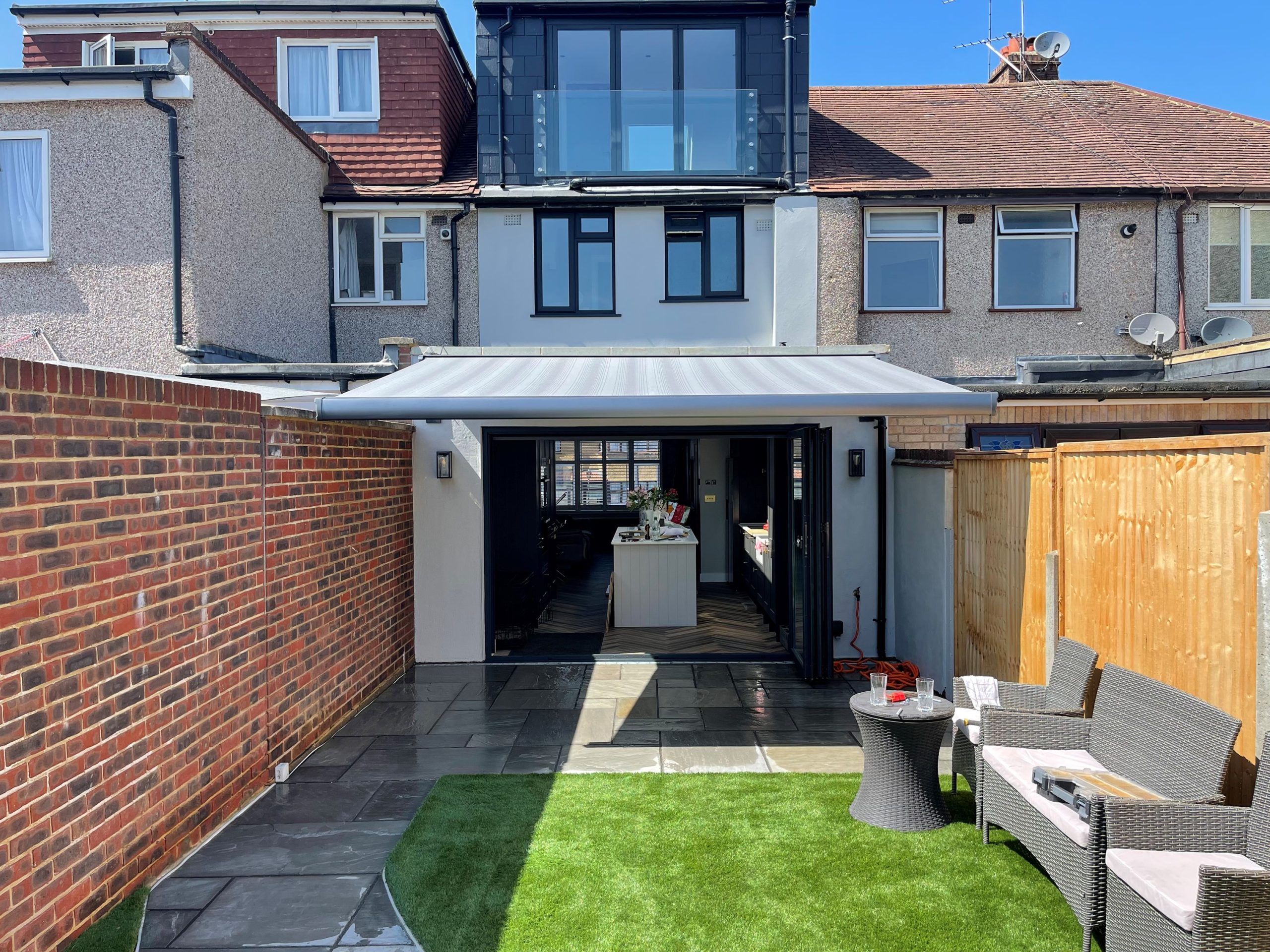 Awning above bifold doors shading a garden dining table