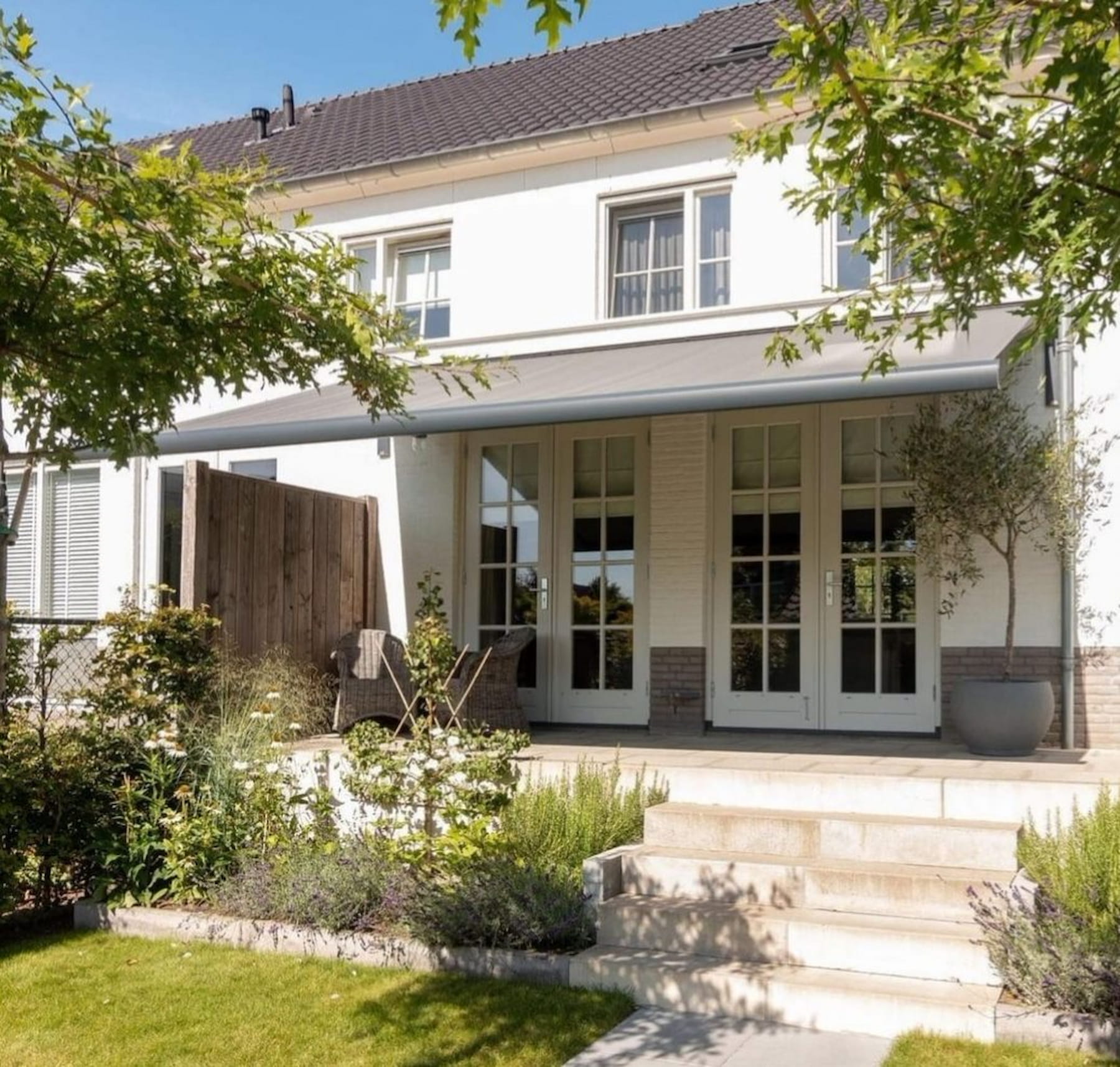 Awning fitted above bifold doors on a London house, shading a garden dining table