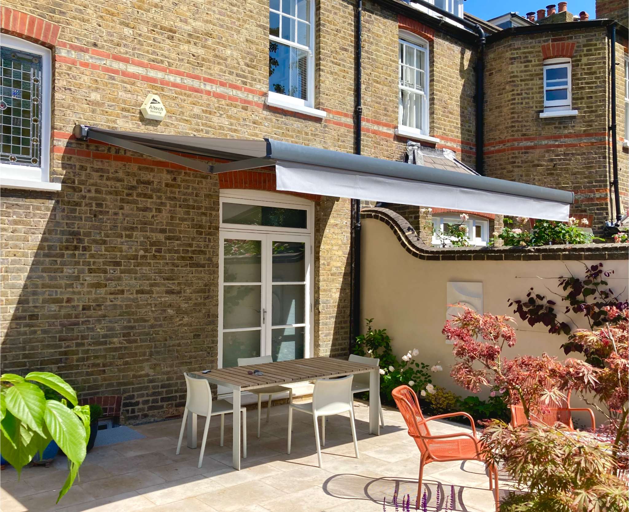 Black and white striped awning extended over a paved terrace with rattan seating